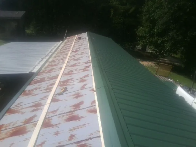 Old rusted panels beside newly installed green metal roofing — Wind Damage Roof Repair by Roofing Brothers in Maggie Valley