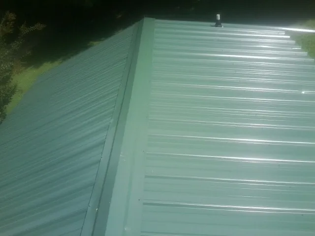 New green metal panels meeting at the ridge of a roof — Flat Roof Repair work by our crew in Maggie Valley