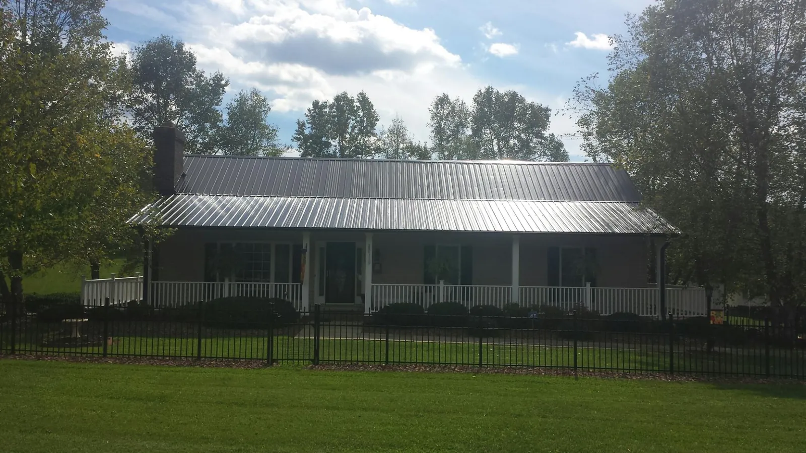 Gray metal roof on a brick ranch with a full width front porch — Gutter Guard Installation work by our crew in Maggie Valley